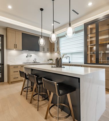 Kitchen interior with bar stools white countertops wooden cabinets pendant lighting extra kitchen sink glass cabinets hardwood floors stainless steel appliances window with coverings blinds drawn