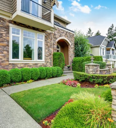 Beautiful curb appeal of American house with stone trim and perfectly trimmed shrubs. Northwest, USA